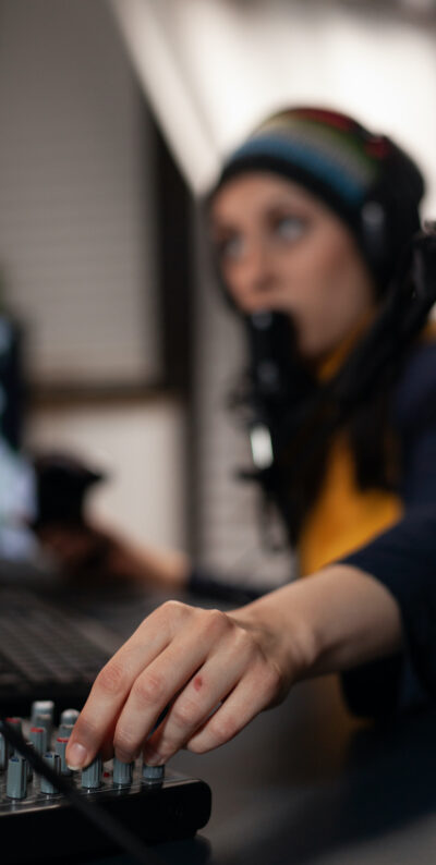 Close up of adult using streaming equipment on desk with headphones and microphone. Gamer talking to audience on broadcast, live streaming on computer. Streamer with electronic gadget
